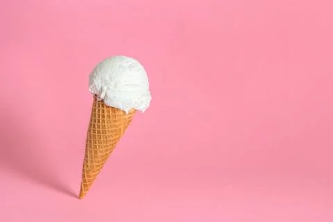 Creative concept of close up falling single wafer cone with ice cream on pink Foto stock