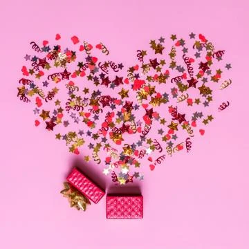 Creative concept with festive decor on pink background. Confetti hearts and s Stock Photos