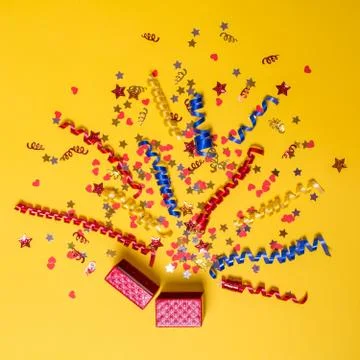 Creative concept with festive decor on yellow background. Explosion of confetti. Stock Photos