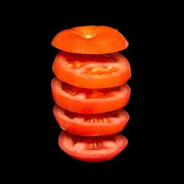 Creative concept with flying tomato. Sliced red tomato isolated on black back Stock-Fotos