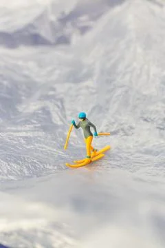 Creative concept image of a tiny figurine skiing down a snowy mountain land.. Foto stock