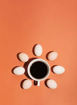 Creative concept made with cup of coffee, shadows and eggs on pastel brown or Stock Photos