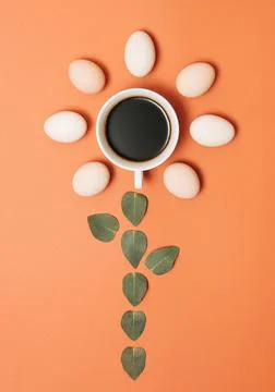 Creative concept made with cup of coffee, green leaves and eggs on pastel bro Stock Photos