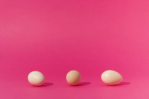 Creative concept made with white eggs on trendy pink background. Minimal east Stock Photos