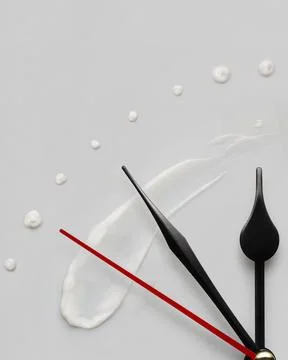 Creative concept photo of clock hands and cream on a grey background Stock Photos