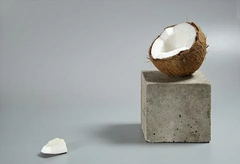 Creative conceptual still life with open coconut balance on concrete cube sta Stock Photos