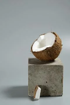 Creative conceptual still life with open coconut balance on concrete cube sta Stock Photos