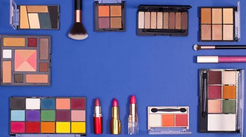Creative copy space frame with make up and cosmetics fashion products on blue Stock Photos