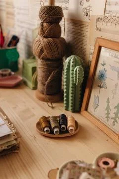 Creative Corner. Details on a wooden work table, scissors, thread, fabrics. Stock Photos