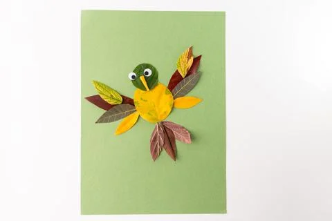 A creative craft project on a green background. Bird made from various leav.. Foto stock