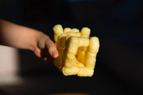 Creative cube made of corn sticks glued with saliva by child hand in warm light Stock Photos