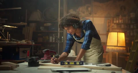 Creative curly Latin carpentry master working at cozy workshop drawing furniture Stock Footage 140431354