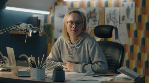 Creative designer in home based studio stops sketching and looks at the camera Video stock 217650678