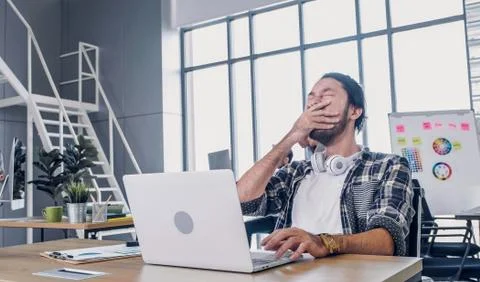 Creative designer yawn while working hard and boring with laptop at modern of Stock Photos