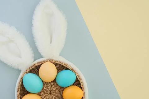 Creative Easter background with eggs in pastel colors, bunny ears, basket on a Stock Photos