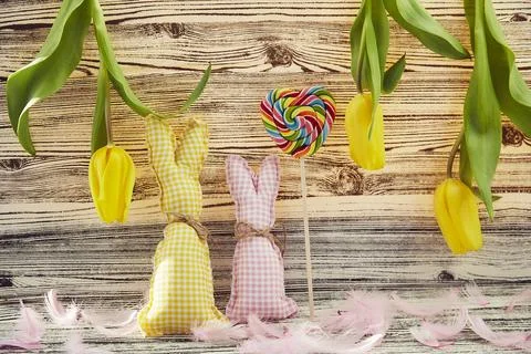Creative Easter background: handmade bunnies, yellow tulips, lollipop in shape Stock Photos