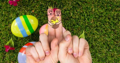 Creative easter bunnies cartoons on index fingers over eggs and grass Stock Photos