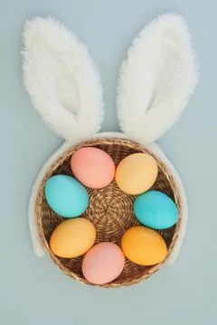 Creative easter composition of easter eggs in a basket and bunny ears on a blue Stock Photos