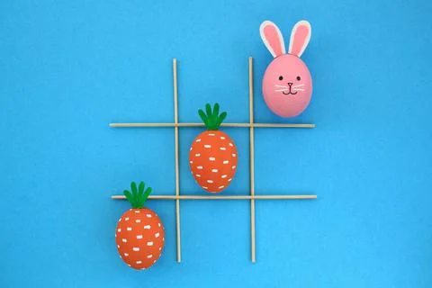 Creative easter eggs with carrot and bunnies on blue background Stock Photos