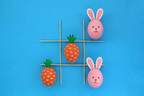 Creative easter eggs with carrot and bunnies on blue background Stock Photos