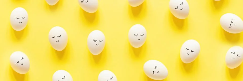 Creative easter eggs with cute face and sleepy eyes on pastel yellow backgrou Stock Photos