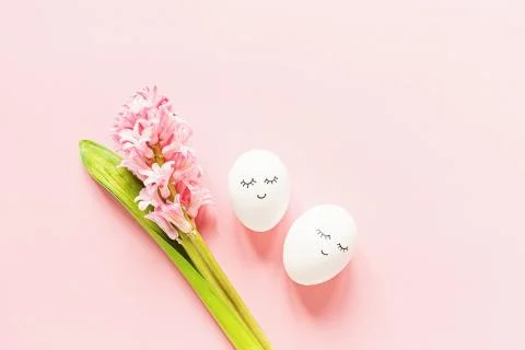 Creative easter eggs with cute face and sleepy eyes and hyacinth flower on pa Stock Photos