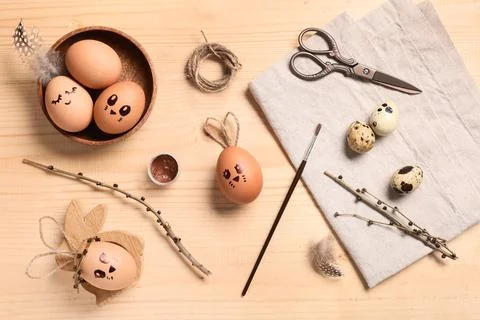 Creative Easter eggs with decorations and supplies on brown wooden background Stock Photos