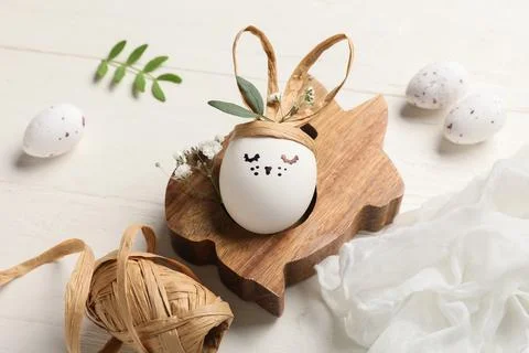 Creative Easter eggs with rabbit and supplies on white wooden background Stock Photos