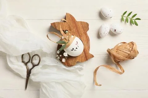 Creative Easter eggs with rabbit and supplies on white wooden background Stock Photos