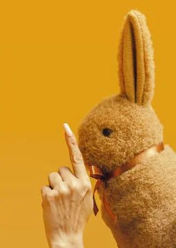Creative Easter Minimal Concept. A woman's hand shows the rabbit to be quet Stock Photos