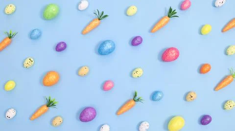 Creative Easter neatly pattern with colorful eggs and carrots on bright paste Stock Photos