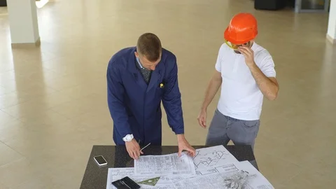 Creative engineer coworkers working on plan in hardhat Stock Footage 70797515