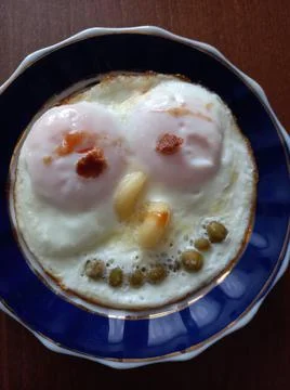 Creative face shape for breakfast of scrambled eggs with green peas on a plate Stock Photos