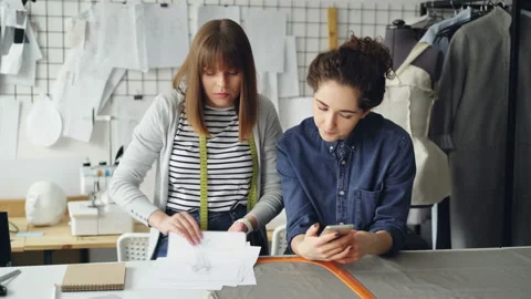 Creative fashion designers are watching sketches working near sewing desk. Young Stock Footage