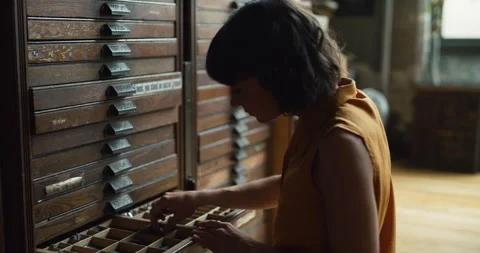 Creative female artist going through drawers of letters for printmaking in inter Stock Footage 199458775