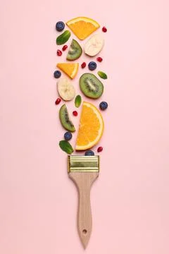 Creative flat lay composition with paint brush, fruits and berries on beige b Stock Photos