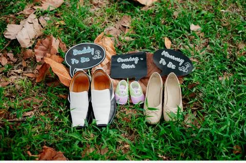 A creative flat lay on grass featuring men's, women's, and baby shoes Stock Photos