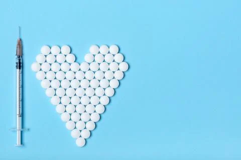 Creative flat lay overhead composition with syringe and heart made of white r Foto stock
