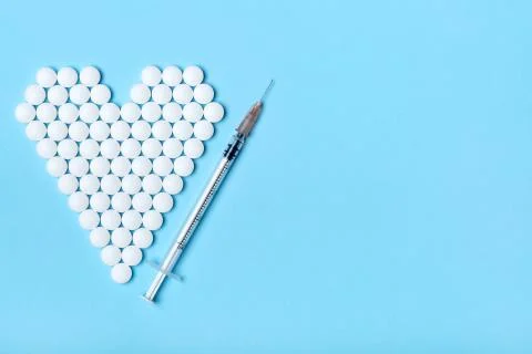 Creative flat lay overhead composition with syringe and heart made of white r Stock Photos