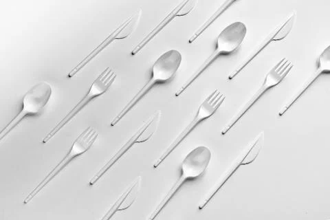 Creative flat lay of plastic forks spoons and knifes pattern Stock Photos