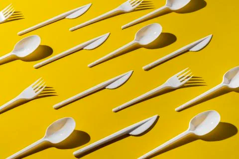 Creative flat lay of plastic forks spoons and knifes pattern Stock Photos