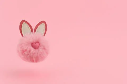 Creative flying fluffy rabbit pompon flies on a pink background. Stock Photos