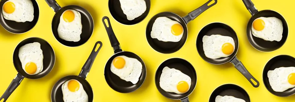 Creative food pattern with fried eggs on pans over yellow background. Top view Stock Photos
