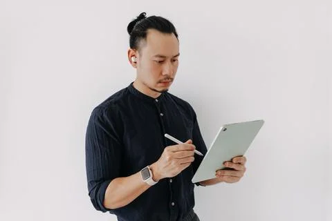 Creative freelance man with earbuds work with tablet isolate on white. Фото