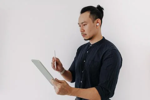 Creative freelance man with earbuds work with tablet isolate on white. Stock-Fotos