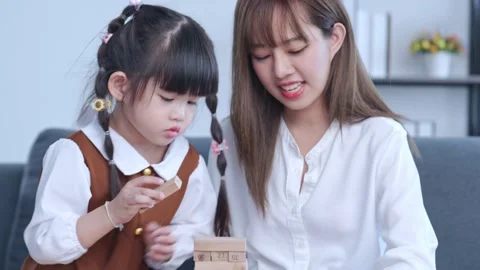 Creative game. Cute mum and her child playing with wooden block bricks toy Stock Footage 220641981