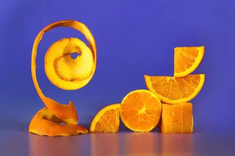 Creative geometry composition of cut orange and peel on violet-blue background Stock Photos
