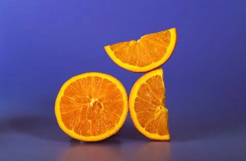 Creative geometry composition of cut orange pieces on the violet-blue background Stock Photos