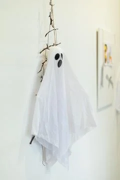 Creative ghost decoration made of white fabric and twigs hanging on a wall for Stock Photos