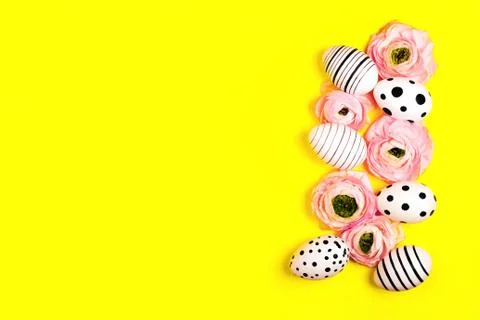 Creative graphic eggs and ranunculus flowers on bright yellow background. Stock Photos